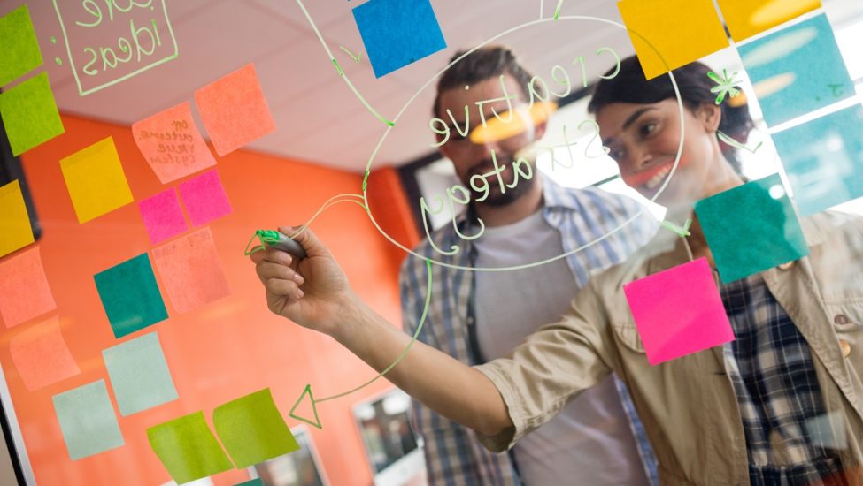 Male and female executives discussing over sticky notes in office